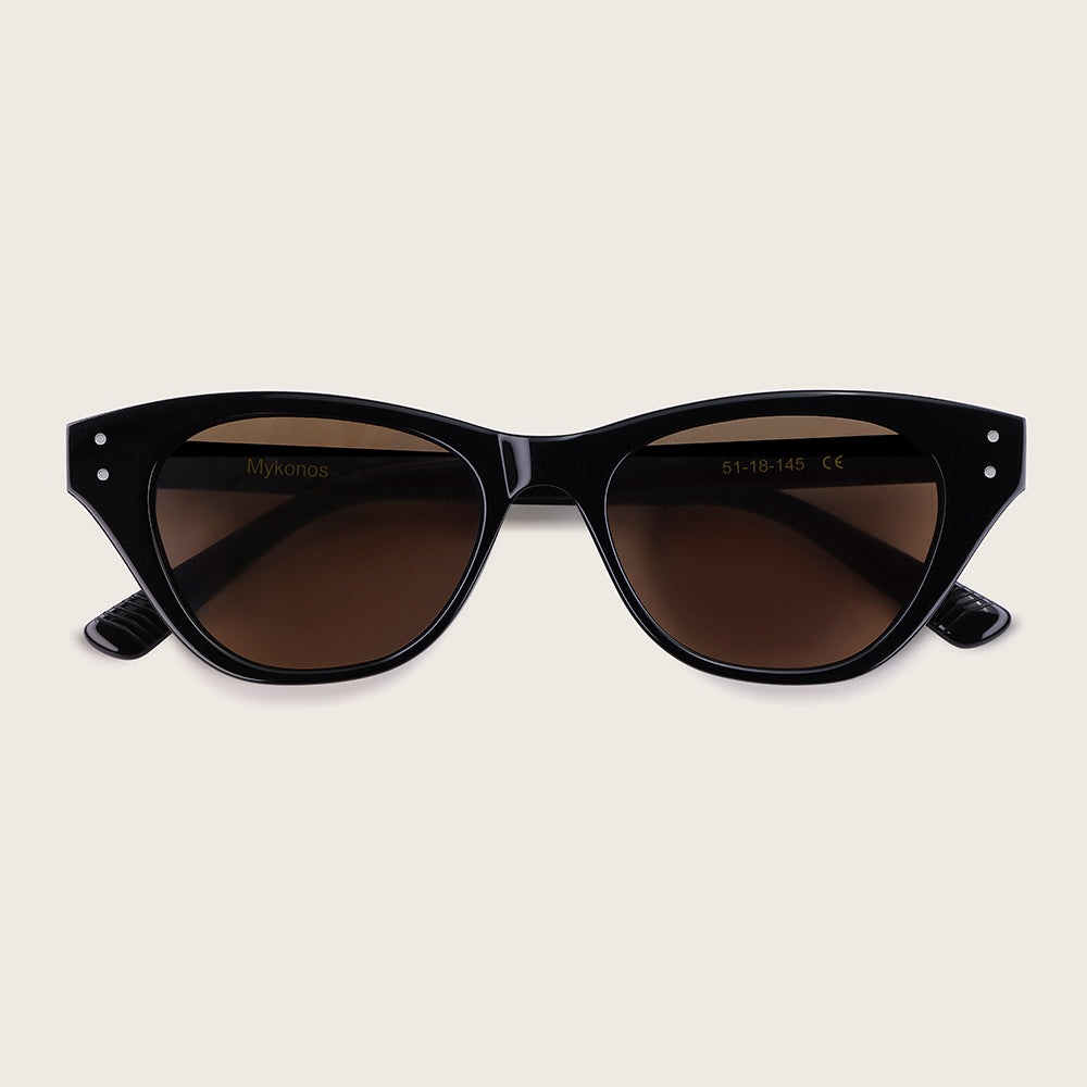 Black cat-eye sunglasses with brown lenses on a beige background