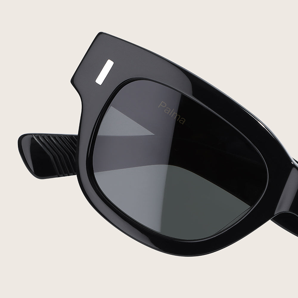 Black sunglasses with a reflective lens on a beige background