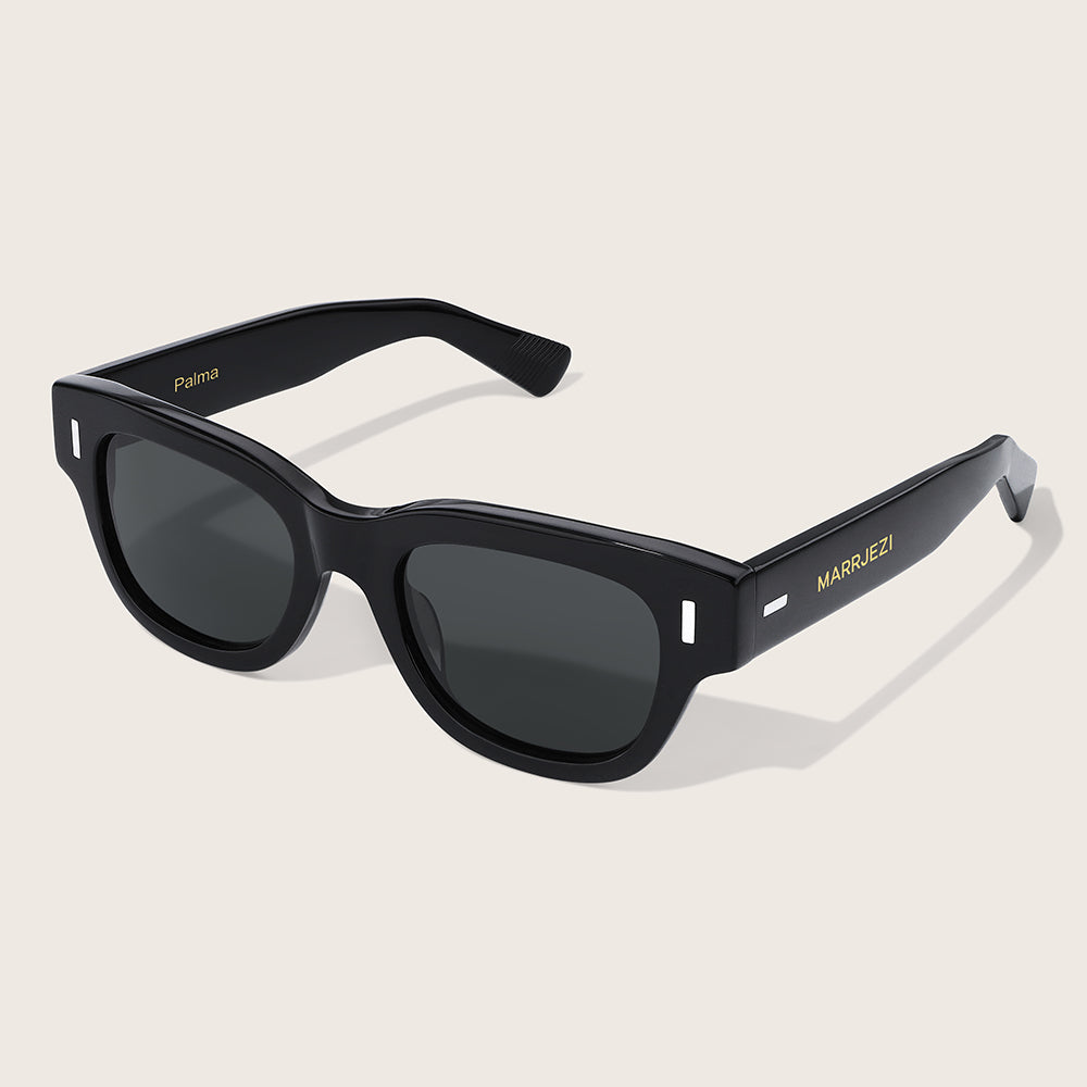 Black sunglasses with 'MARRJEZI' branding on a beige background