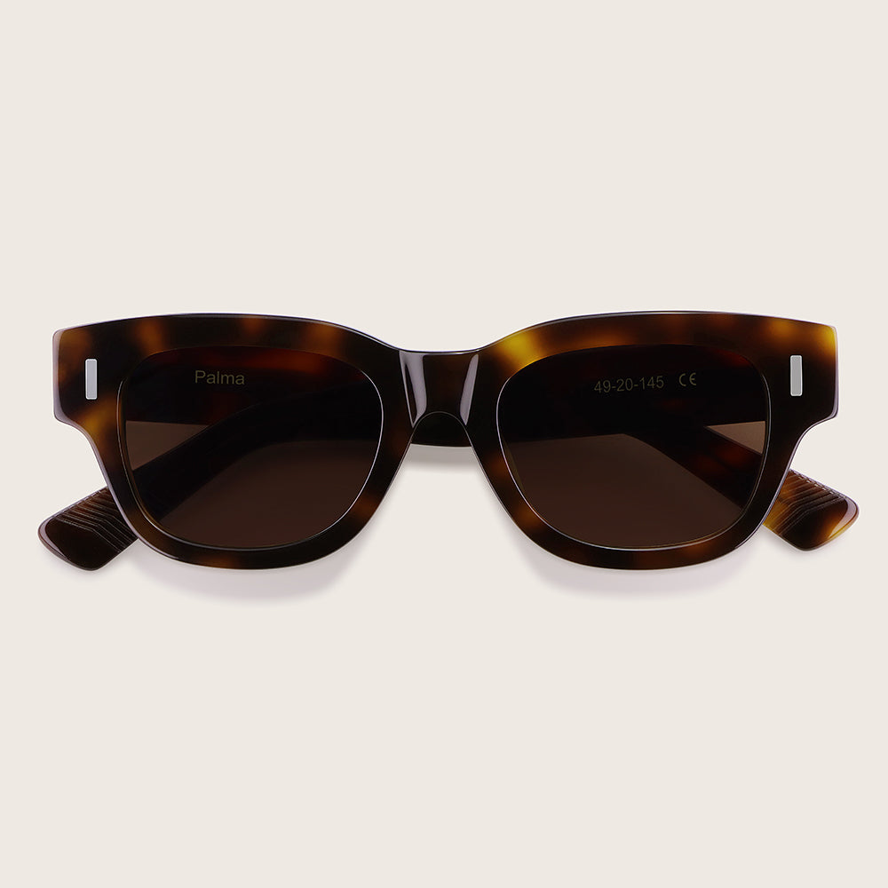 Tortoiseshell sunglasses with dark lenses on a light beige background