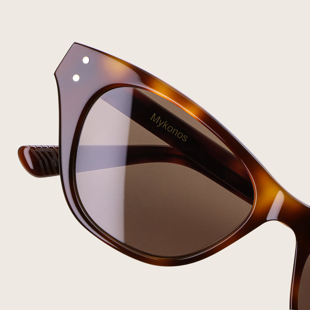 Sunglasses with tortoiseshell frame and dark lenses on a light beige background