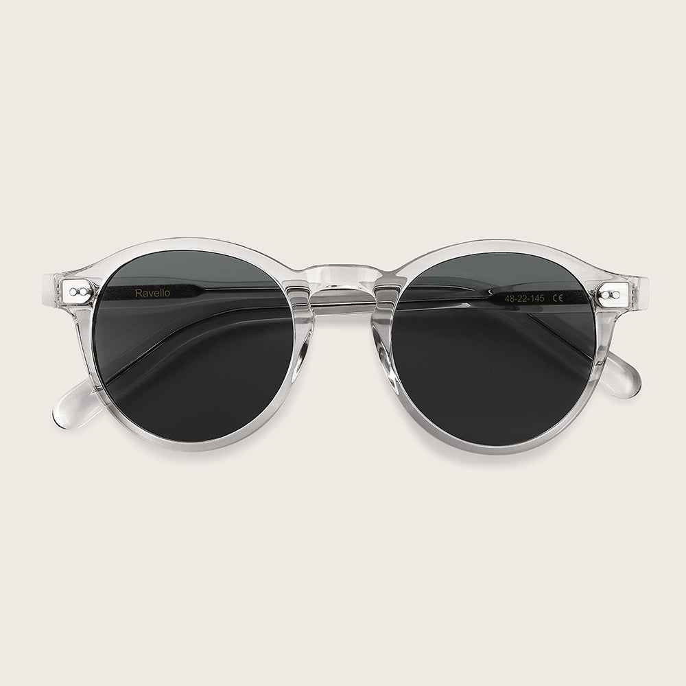 Clear frame sunglasses with dark lenses on a light beige background
