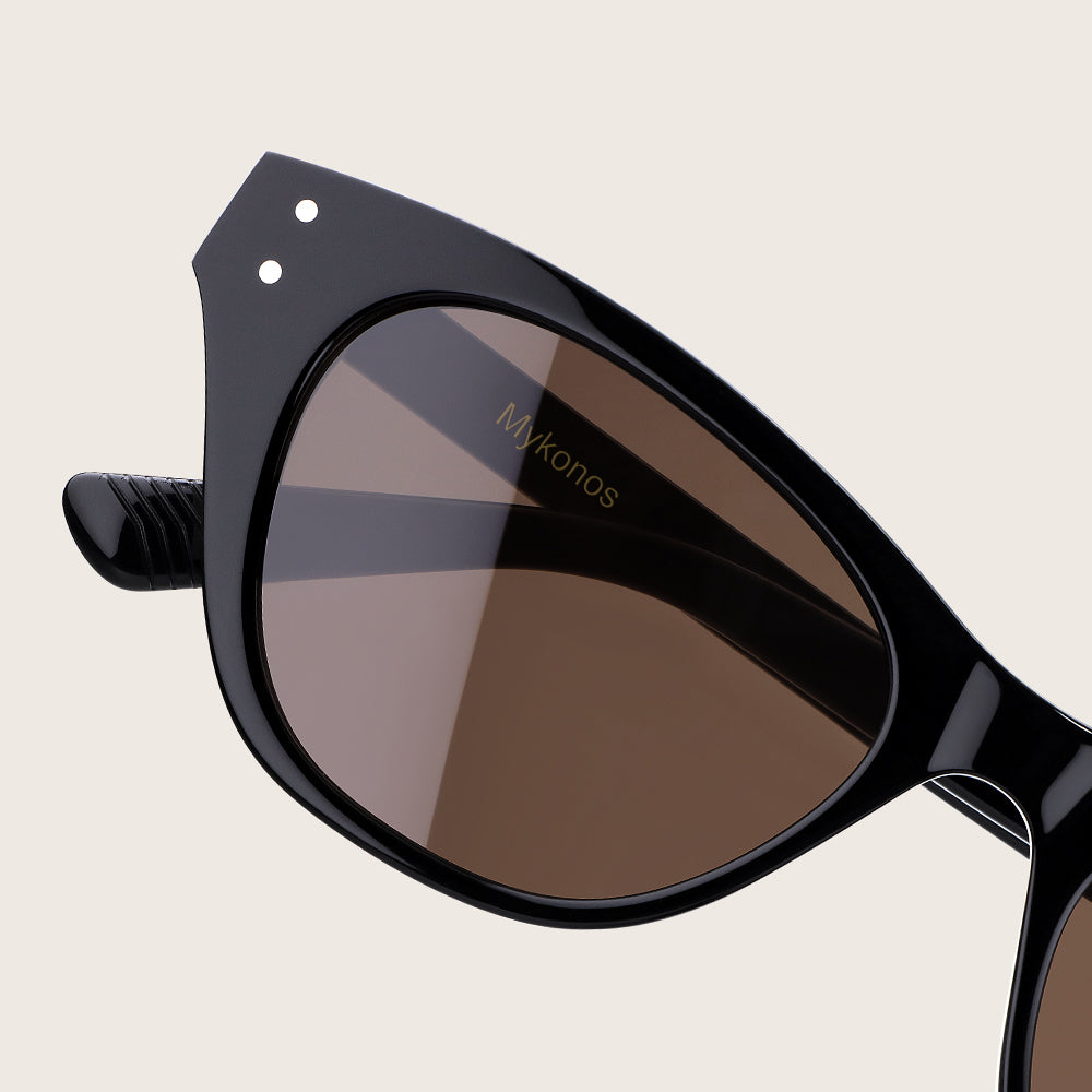 Black sunglasses with 'Mykonos' branding on a beige background