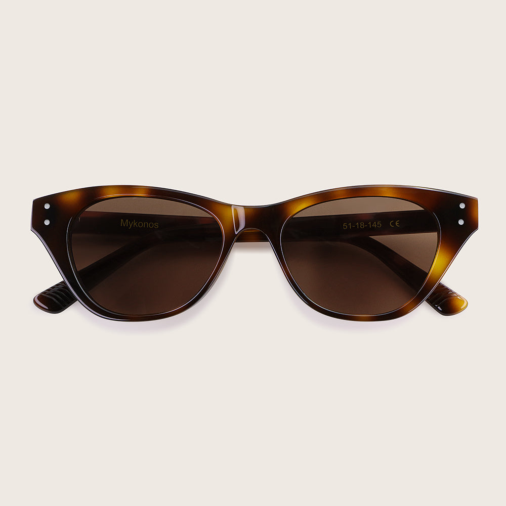 Tortoiseshell sunglasses with brown lenses on a light beige background